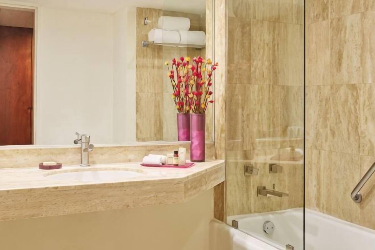 A bathroom with a marble sink, a glass shower enclosure, and a mirror.