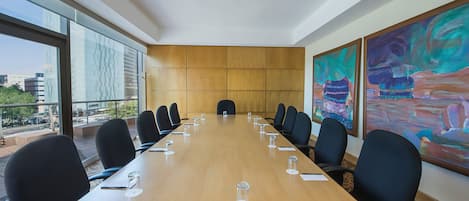 A conference room with a long table, black chairs, and large windows.