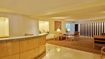 A hotel lobby with a reception desk, seating area, and a large mirror.