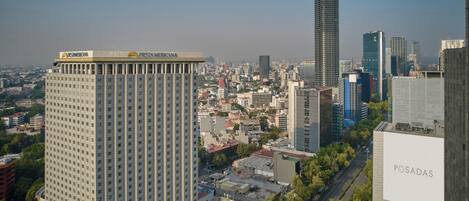 A high-rise hotel with a prominent 'FESTA AMERICA' sign, surrounded by a dense urban cityscape with various buildings and a clear sky.