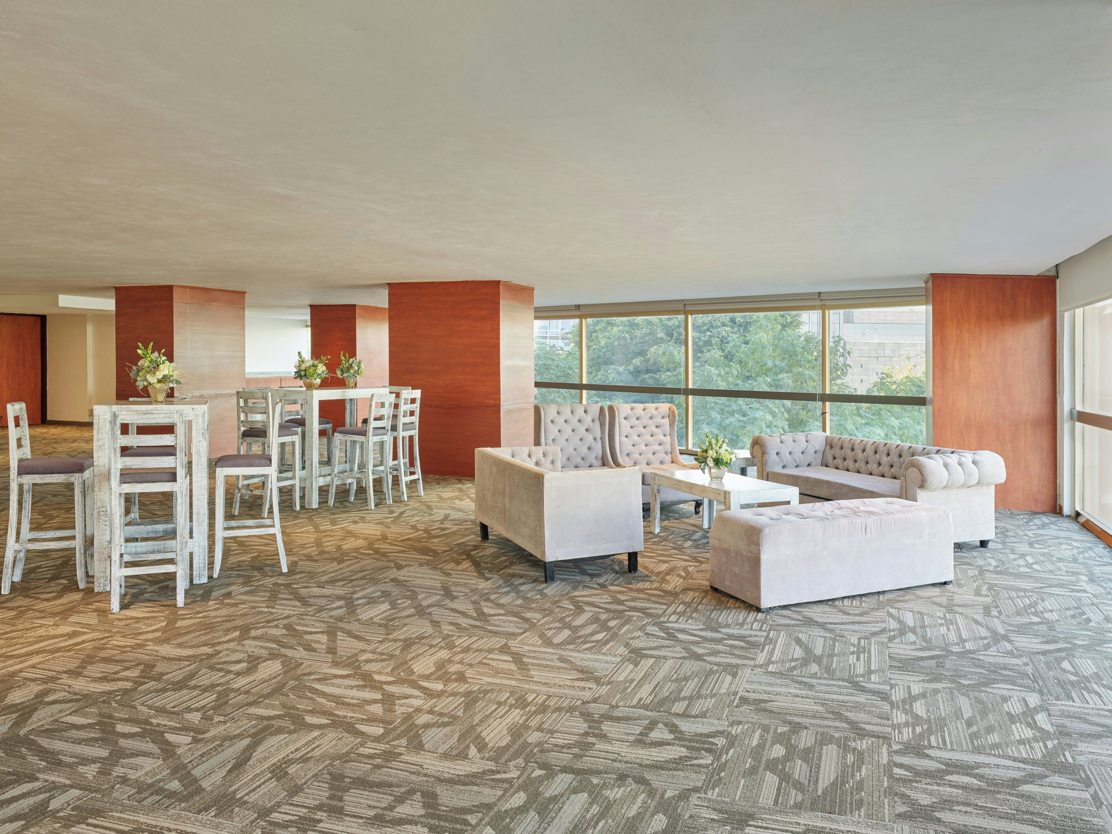 A spacious room with a dining area, sofas, and large windows.