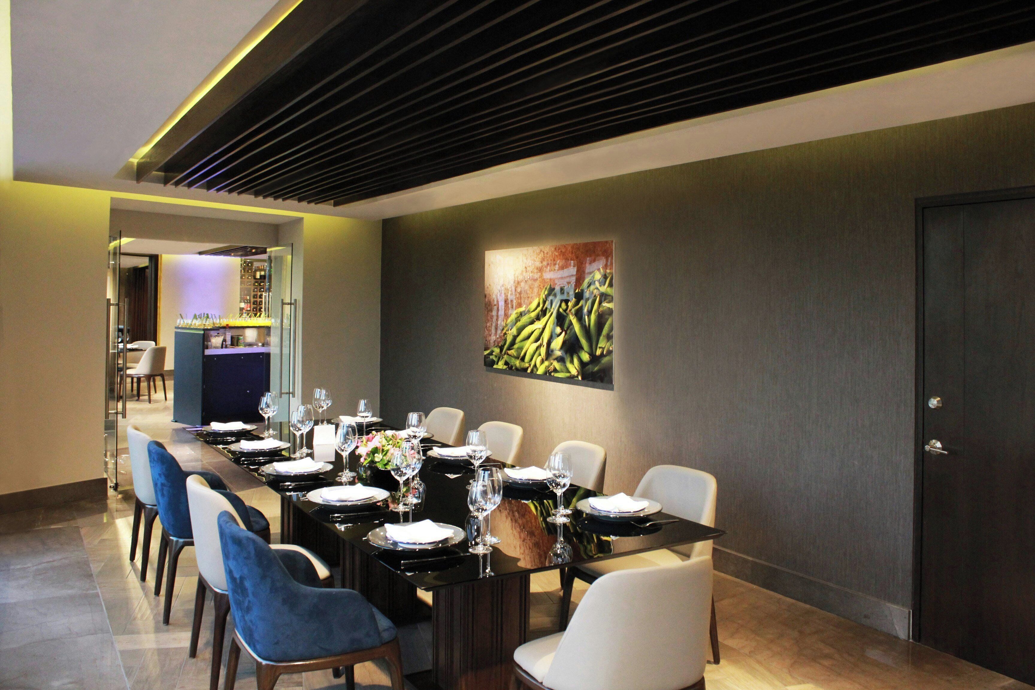 A dining area with a long table set for a meal, chairs, and a wall-mounted artwork.