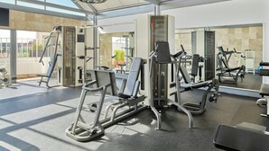 A gym with various exercise machines, a large mirror, and a view of the outside. - Fiesta Americana Reforma (Mexico City)