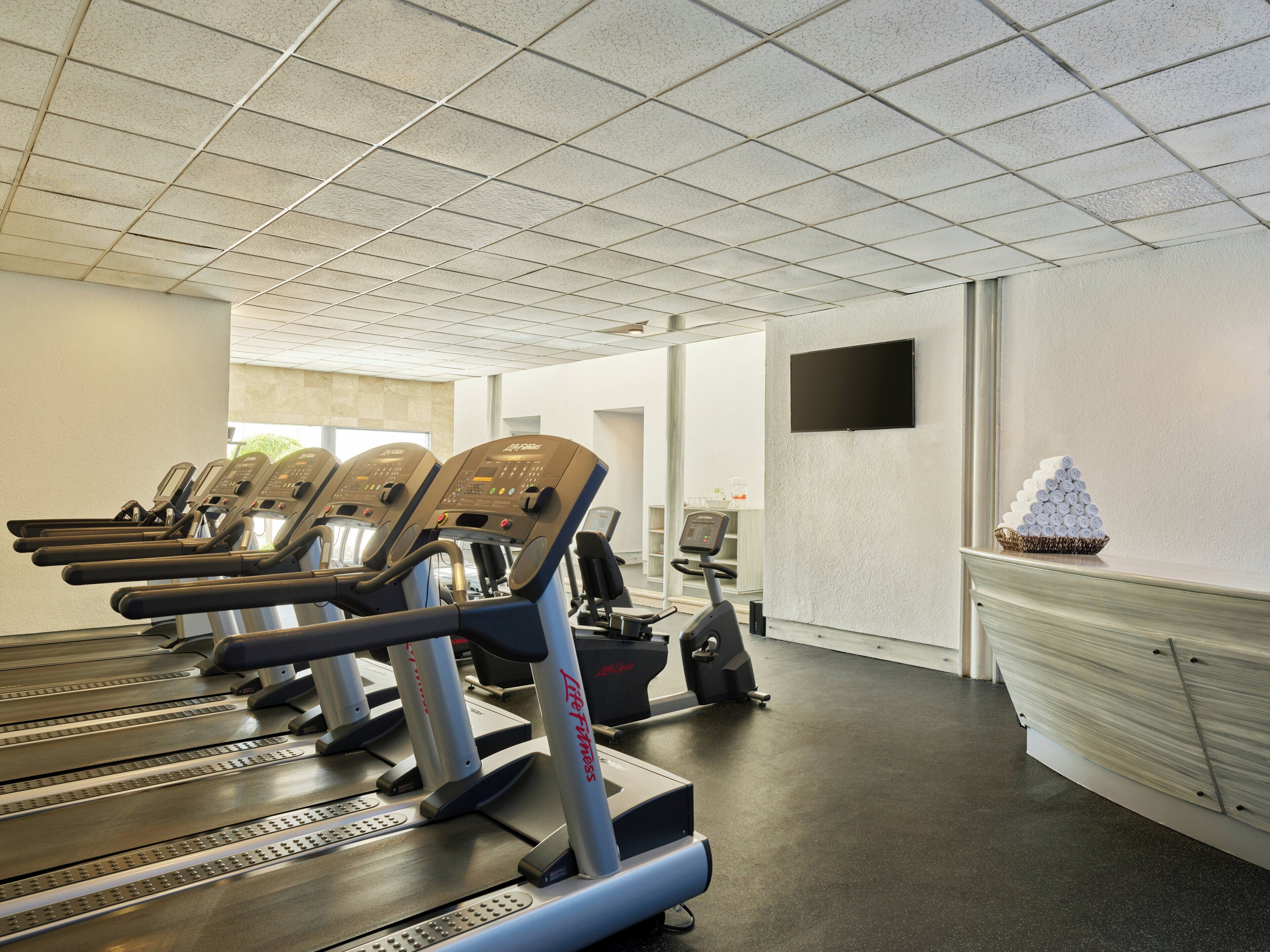 A gym with treadmills, a stationary bike, and a wall-mounted TV.