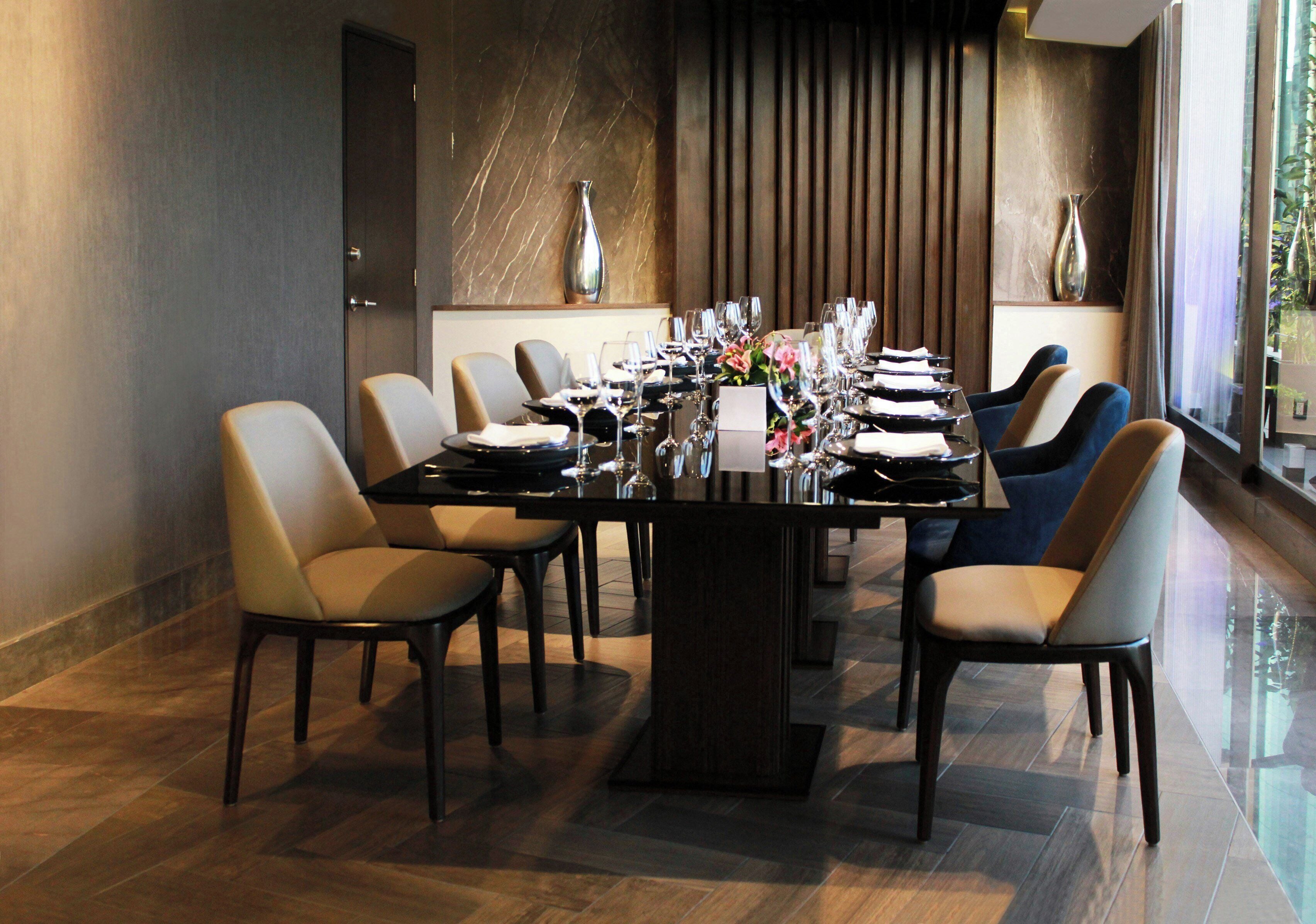 Un espace repas avec une longue table dressée pour accueillir plusieurs personnes, des chaises et un vase de fleurs.