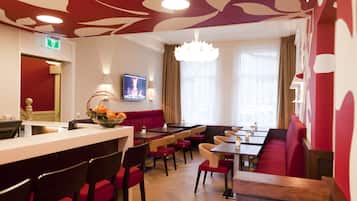 Een restaurant met een rood-wit kleurenschema, houten meubels en een kroonluchter.