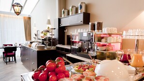 A breakfast buffet with various food items, a coffee machine, and a seating area with a chair and table.