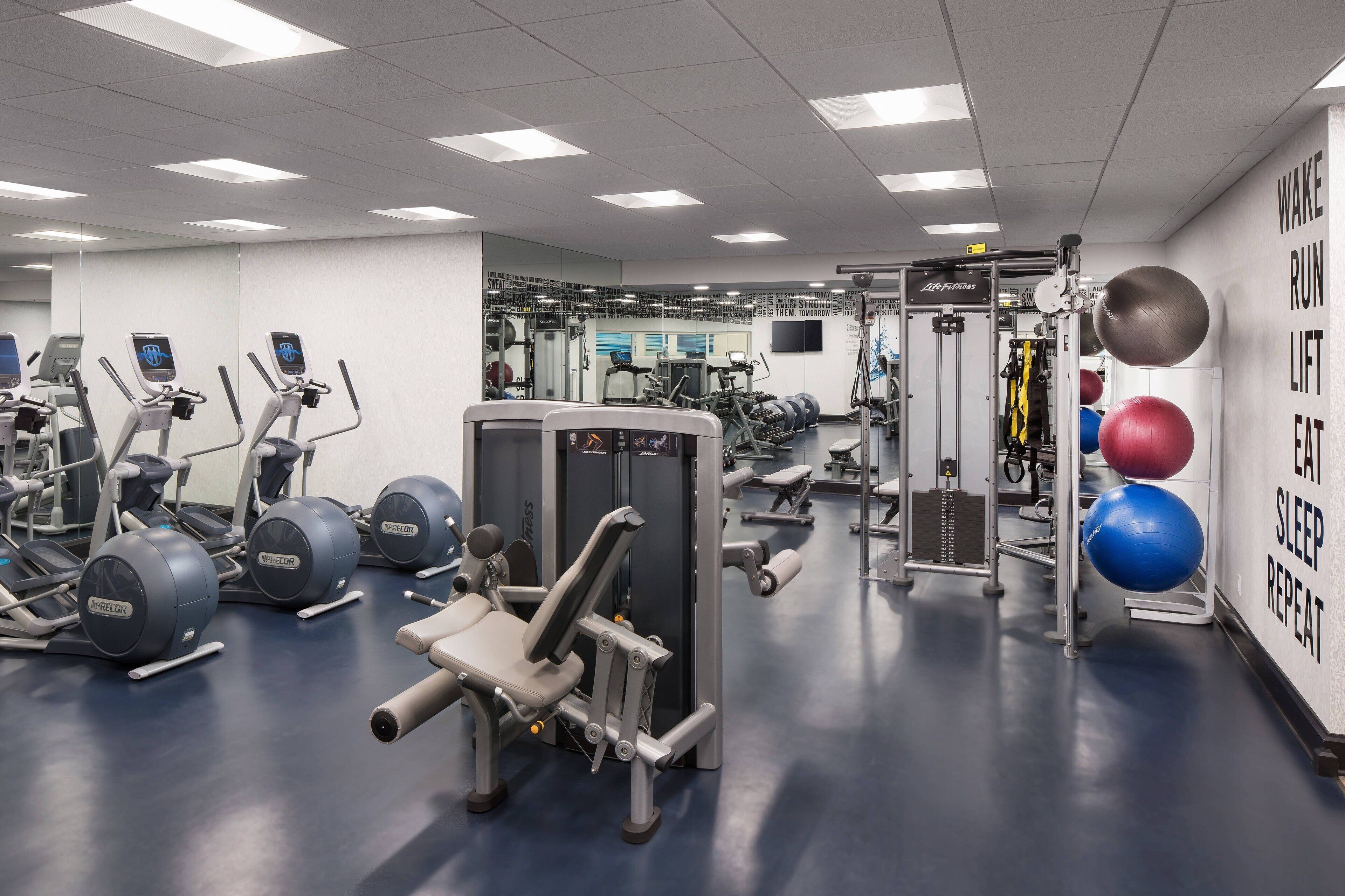 A gym with various exercise equipment, including treadmills, weight machines, and exercise balls.