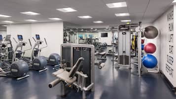 A gym with various exercise equipment, including treadmills, weight machines, and exercise balls.