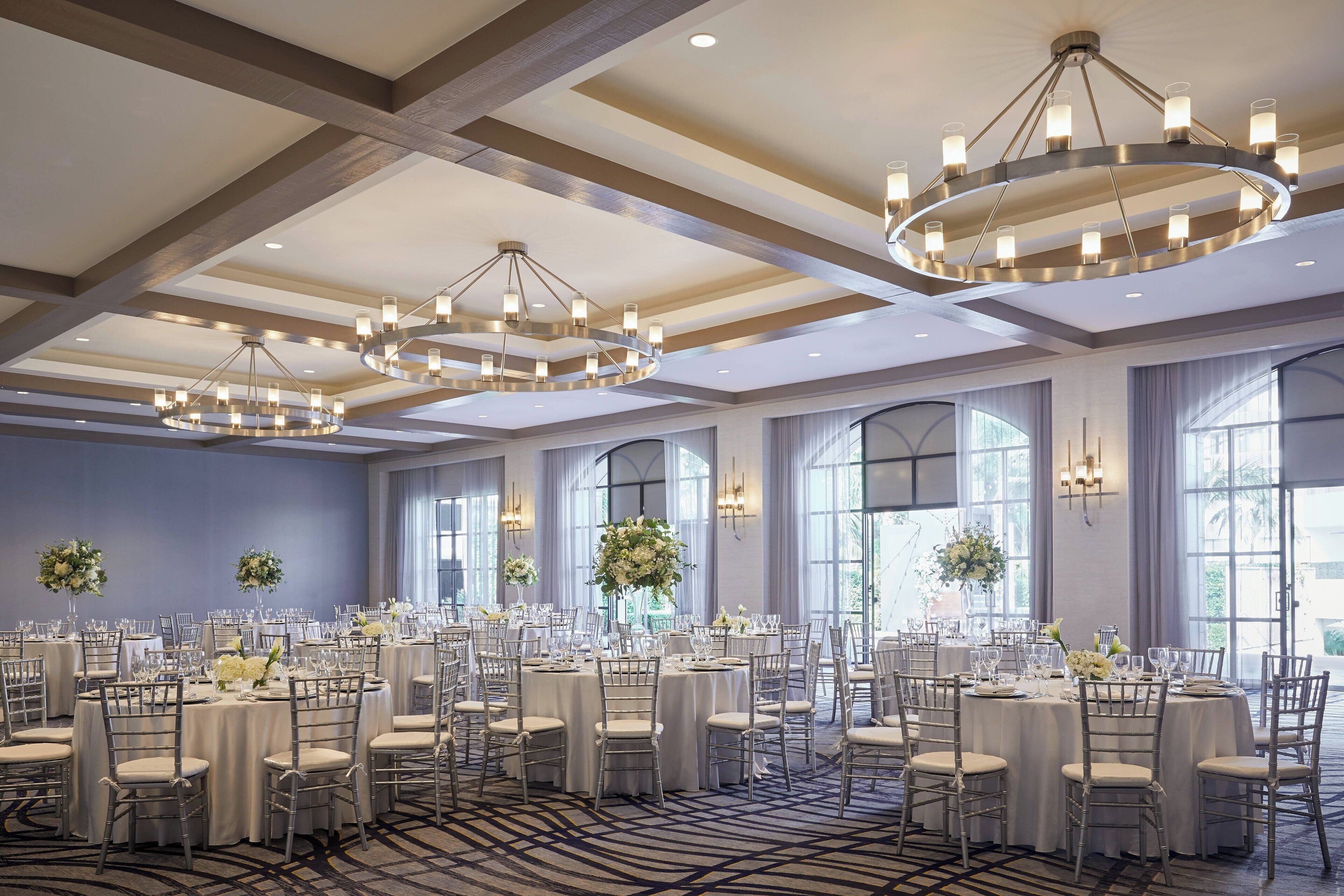 Un salón de banquetes con mesas redondas, sillas y candelabros.