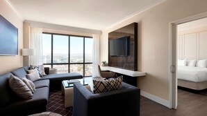 A modern hotel room with a large window, a sofa, a chair, a desk, and a bed. - Irvine Marriott (Irvine)