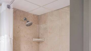 A modern bathroom with a bathtub, shower, and a shelf with toiletries.
