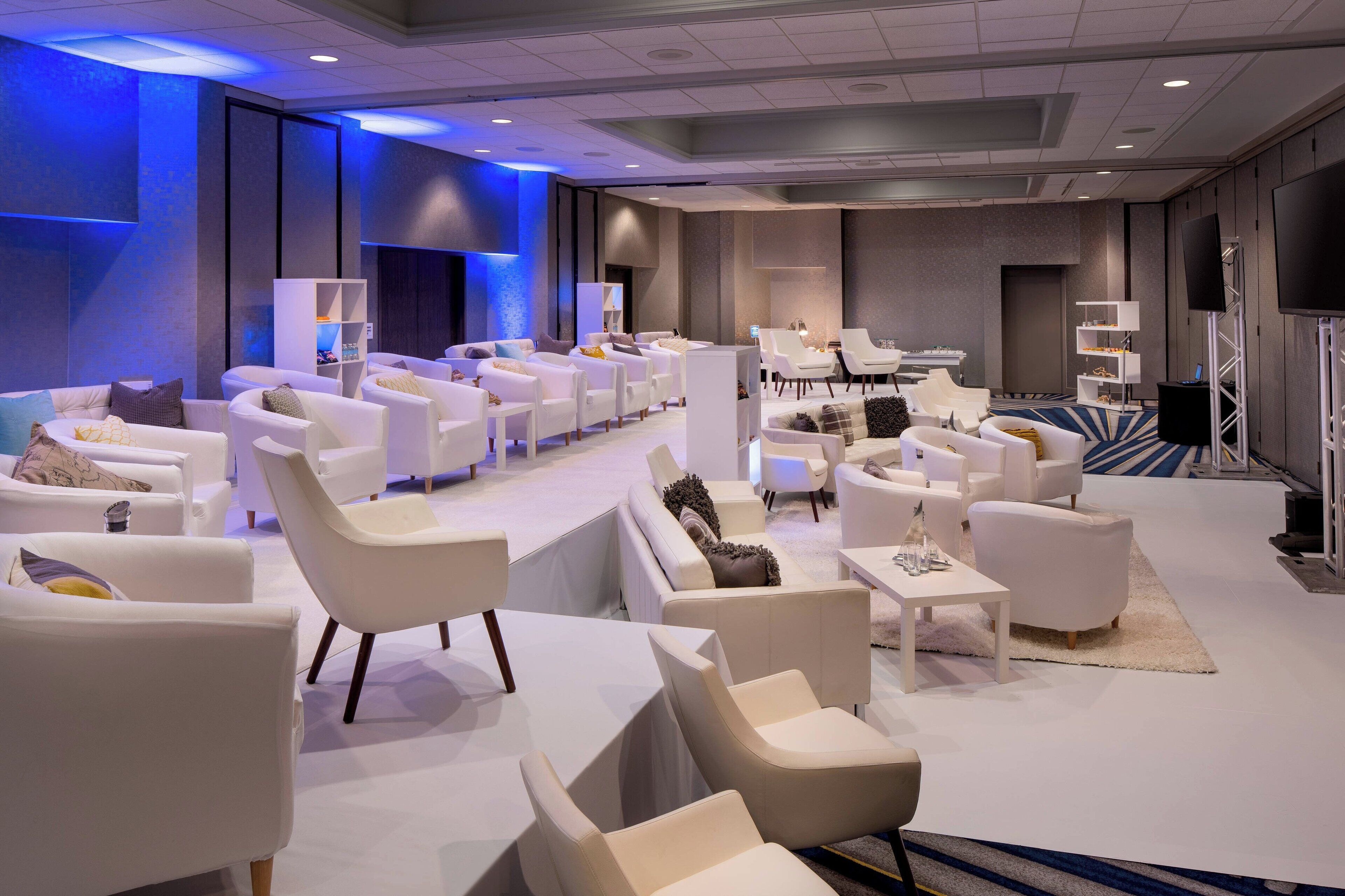 A spacious hotel lobby with multiple seating areas, including sofas and armchairs, arranged in a modern layout.