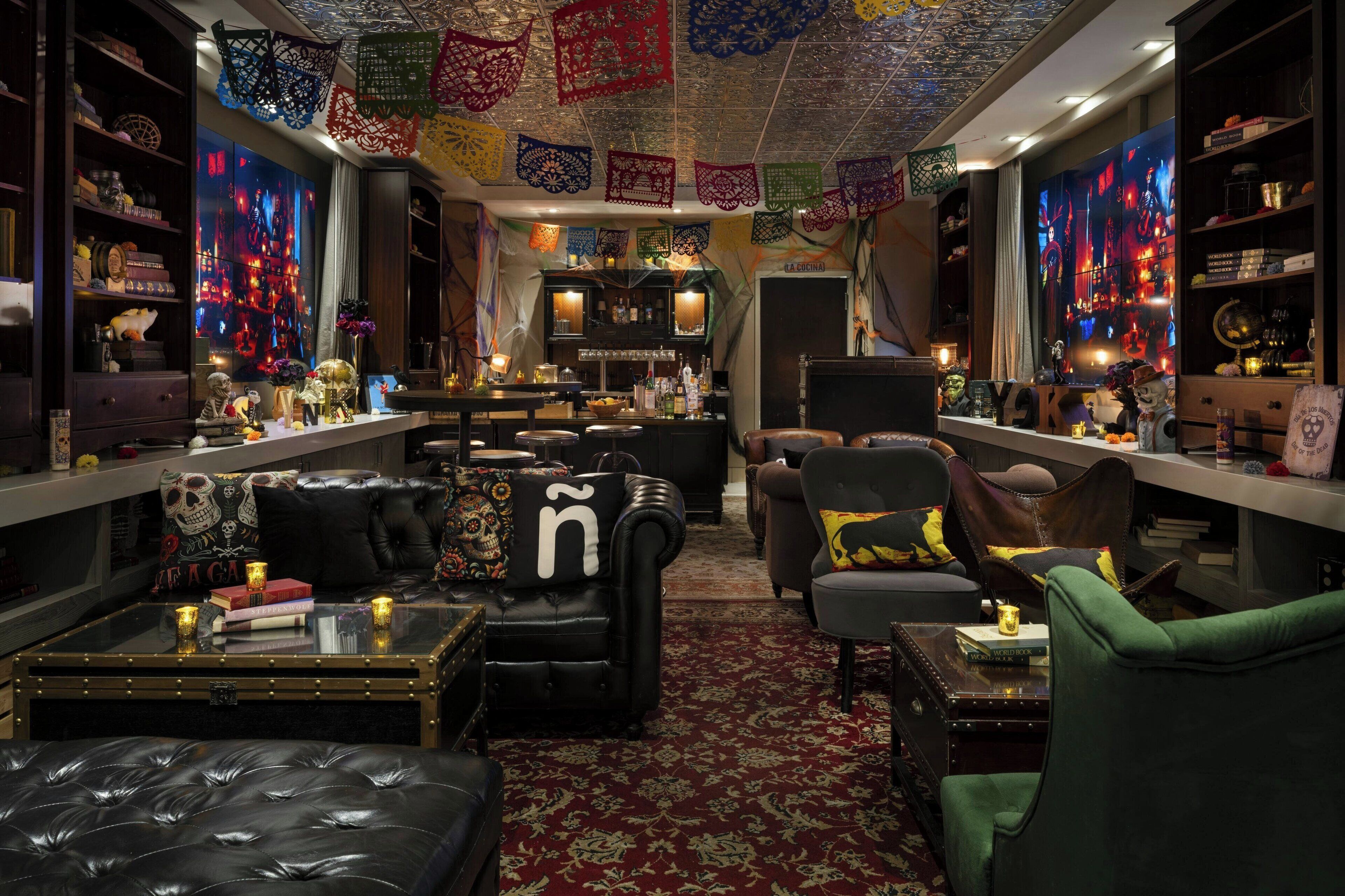 A cozy lounge area with leather sofas, a bar, and a bookshelf filled with books and decorative items.