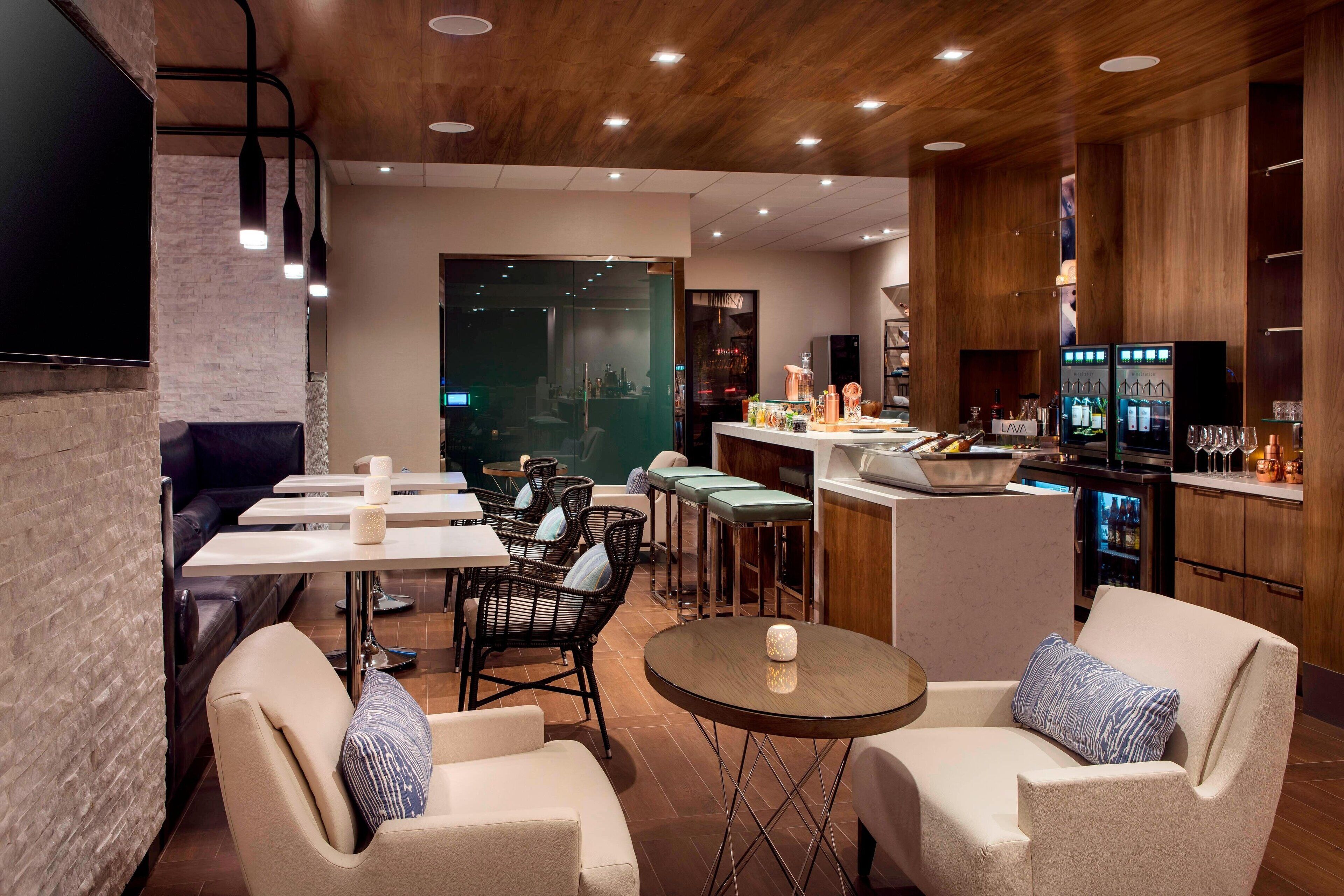 A modern bar area with seating, a bar counter, and a television screen.