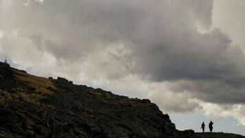 A rocky hill with two people standing at the top.