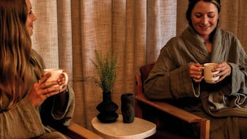 Deux personnes sont assises dans une pièce qui contient une petite table, une chaise et une baignoire sur pieds.
