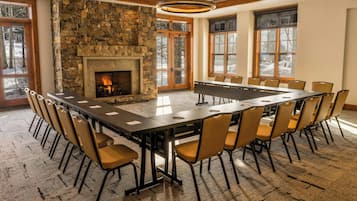 A conference room with a stone fireplace, large windows, and a long table with chairs.