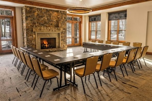 A conference room with a stone fireplace, large windows, and a long table with chairs. - Trailborn Jackson Hole, Outdoor Collection by Marriott Bonvoy (Jackson)
