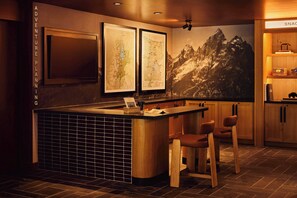 A bar area with a wooden counter, bar stools, and a large map on the wall. - Trailborn Jackson Hole, Outdoor Collection by Marriott Bonvoy (Jackson)