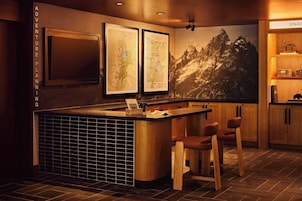 Uma área de bar com balcão de madeira, banquetas e um mapa grande na parede.