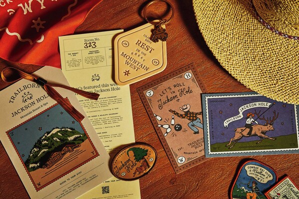 Un conjunto de objetos relacionados con viajes, incluyendo una tarjeta de número de habitación, un llavero, un mapa, una postal y un parche.