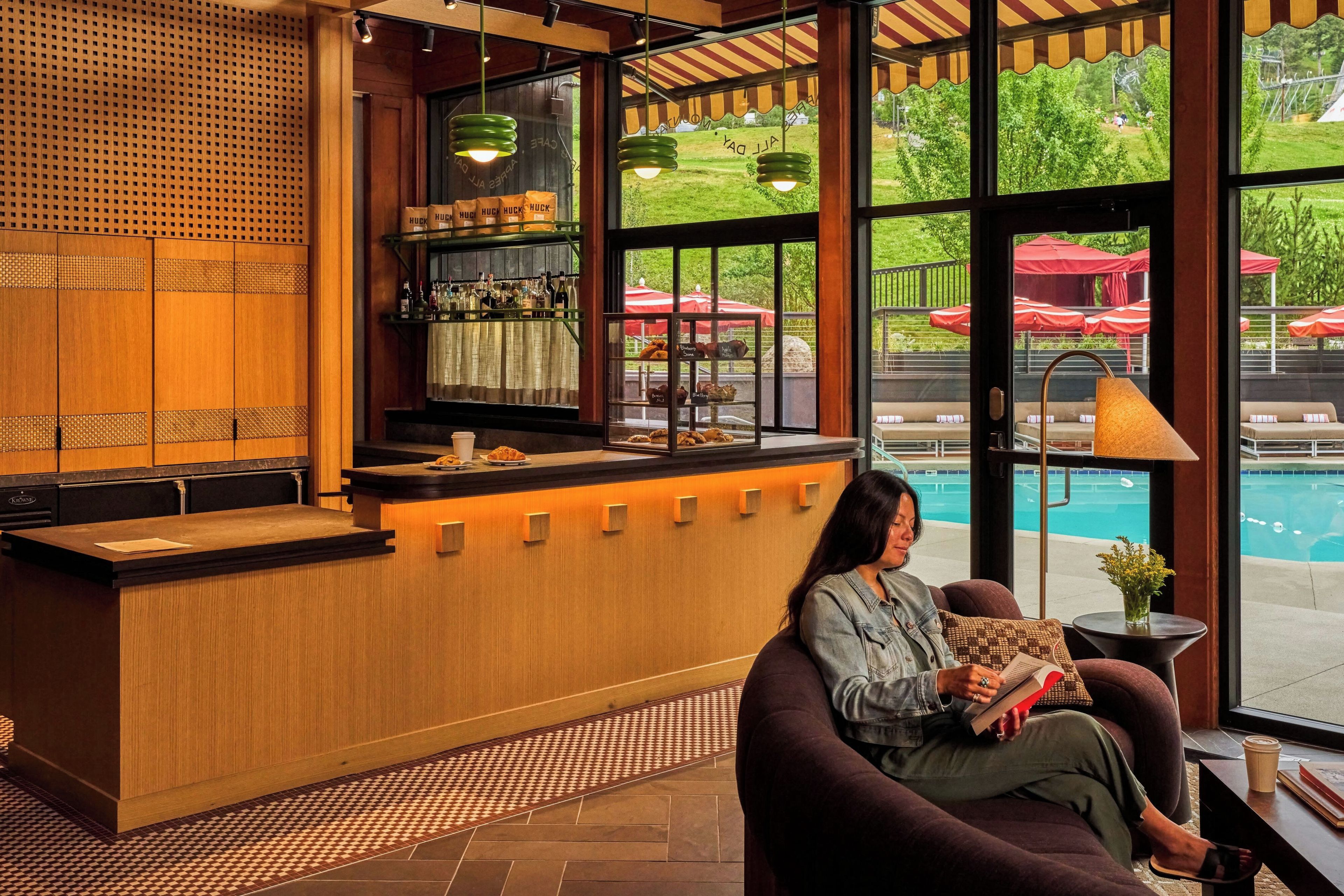 A reception area with a wooden counter, a seating area with a couch, and large windows overlooking a pool.