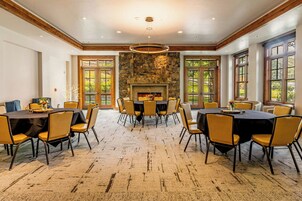 Un comedor espacioso con techos altos, paredes de piedra y grandes ventanales.