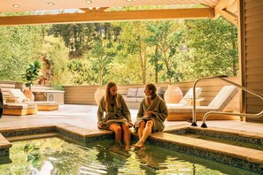 Two individuals seated by a pool with a view of a forested landscape. - Trailborn Jackson Hole, Outdoor Collection by Marriott Bonvoy (Jackson)