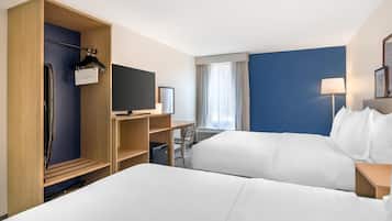 A hotel room with two beds, a TV, a desk, a chair, a wardrobe, and a window with curtains.