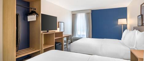 A hotel room with two beds, a TV, a desk, a chair, a wardrobe, and a window with curtains.