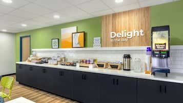 A modern kitchen area with a coffee station, a sign reading "Delight in the day," and a "Minute Maid" water dispenser.