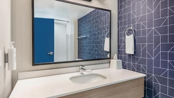 A modern bathroom with a large mirror, a sink, and a towel rack.