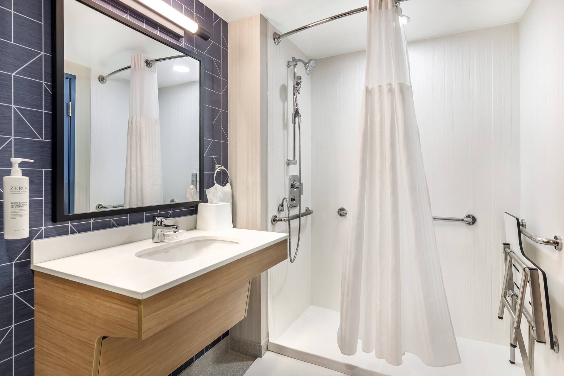 Une salle de bain moderne avec un grand miroir, un lavabo, une douche avec une porte en verre et des toilettes.