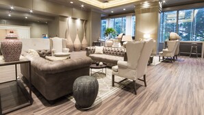 A spacious living area with a sectional sofa, a round coffee table, and a large vase. There is a view of trees through the windows. - Unipark by Oro Verde Hotels (Guayaquil)