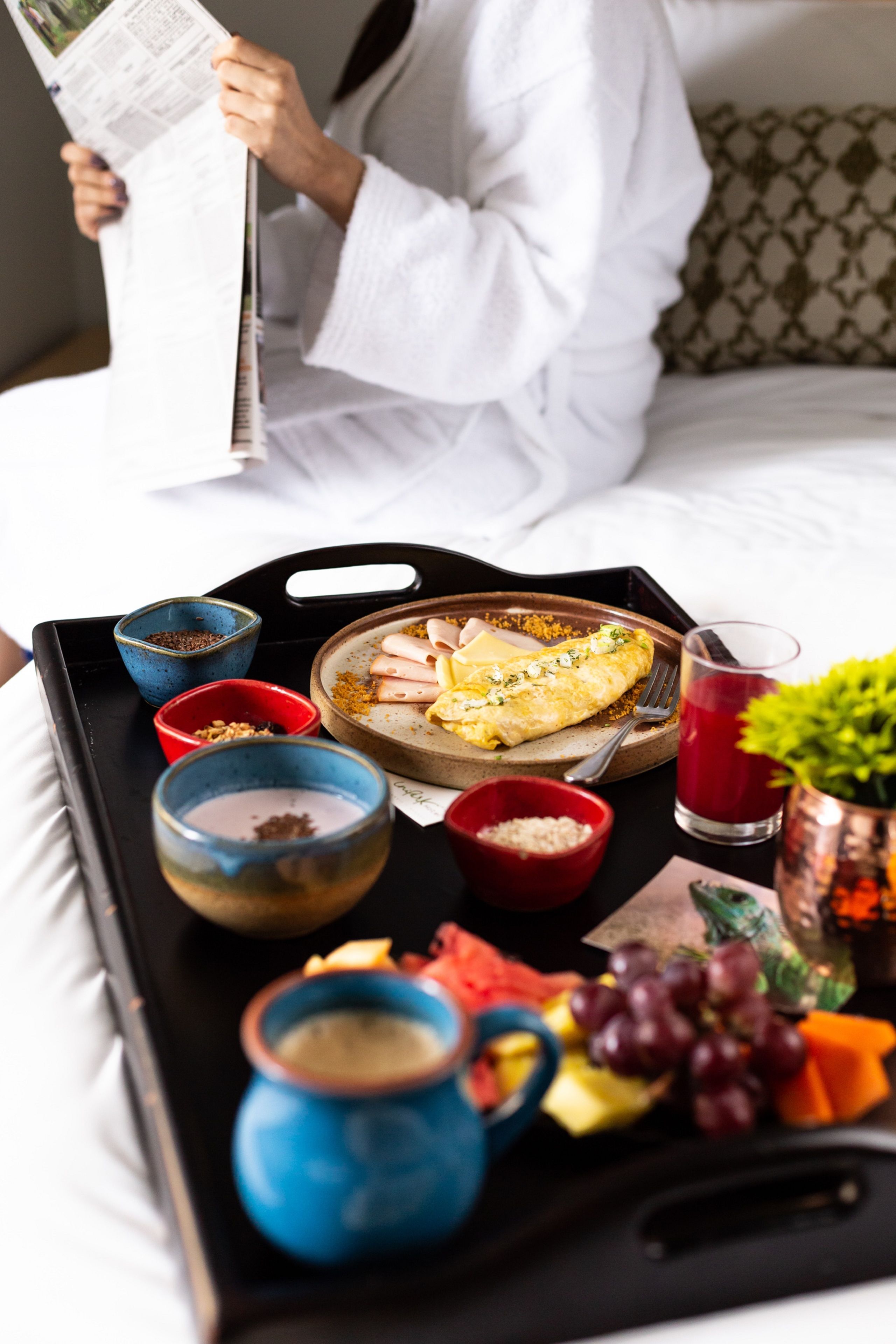 A tray with food and drinks on a bed.
