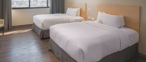 A hotel room with two beds, a large window with curtains, and a view of the cityscape.