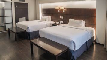 A hotel room with two beds, a bench, a nightstand, and a wall-mounted lamp.