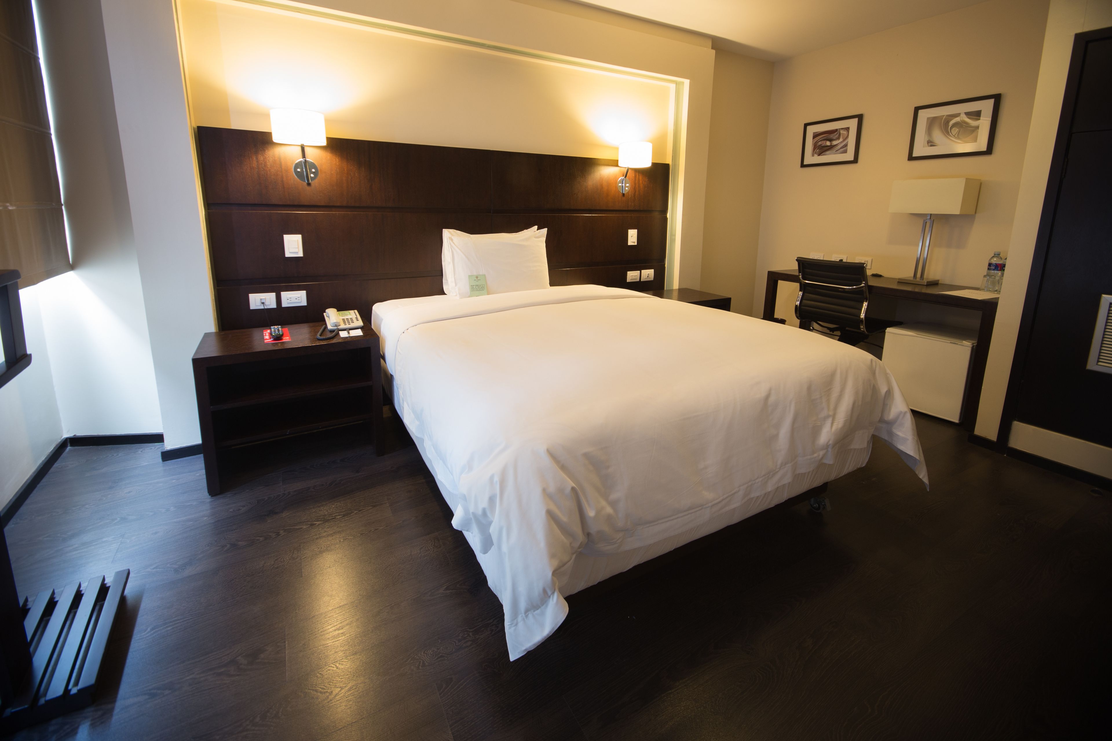 Ein Hotelzimmer mit einem großen Bett, Nachttischen, einem Schreibtisch und einem Sessel.