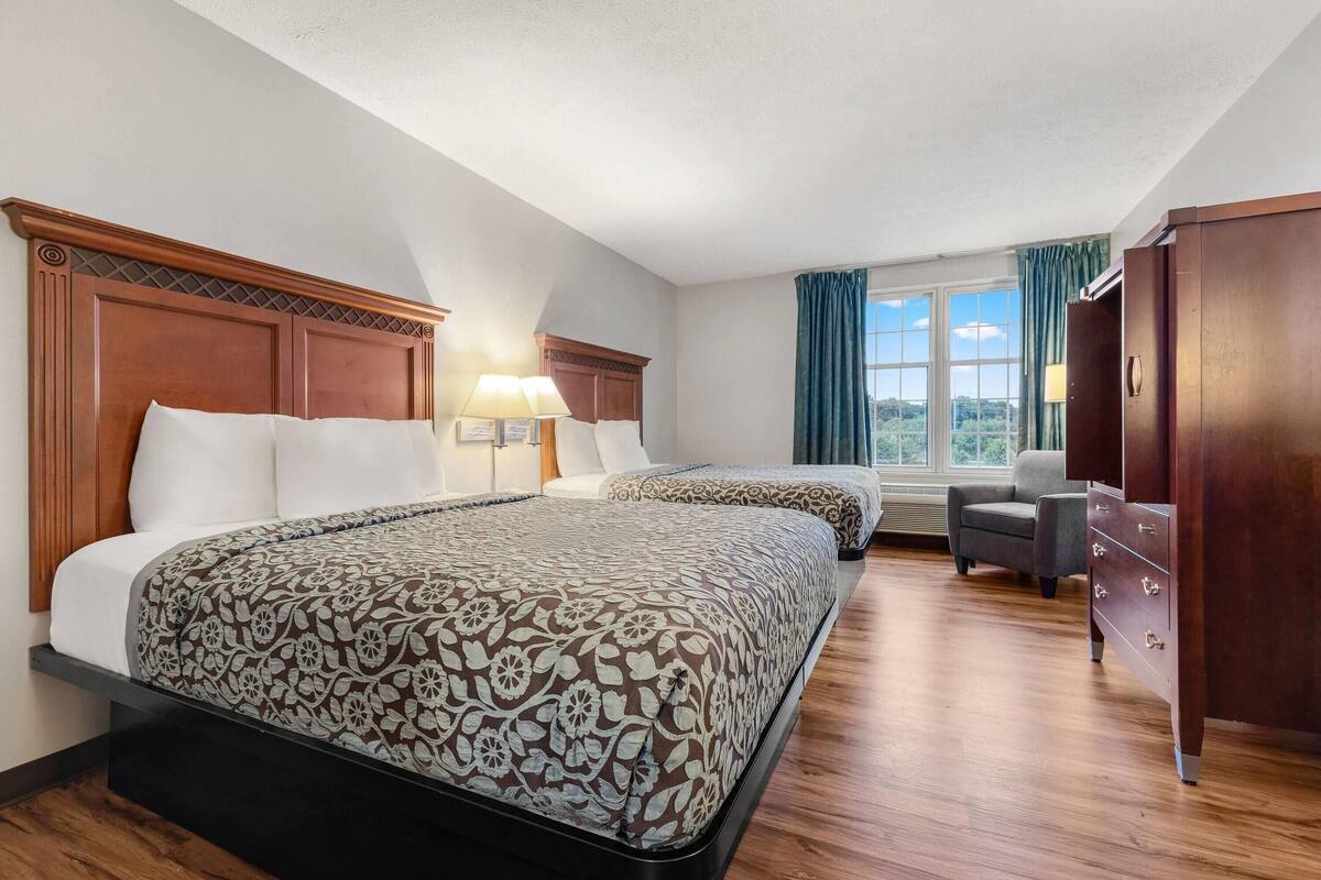 A hotel room with two beds, a desk, and a chair.