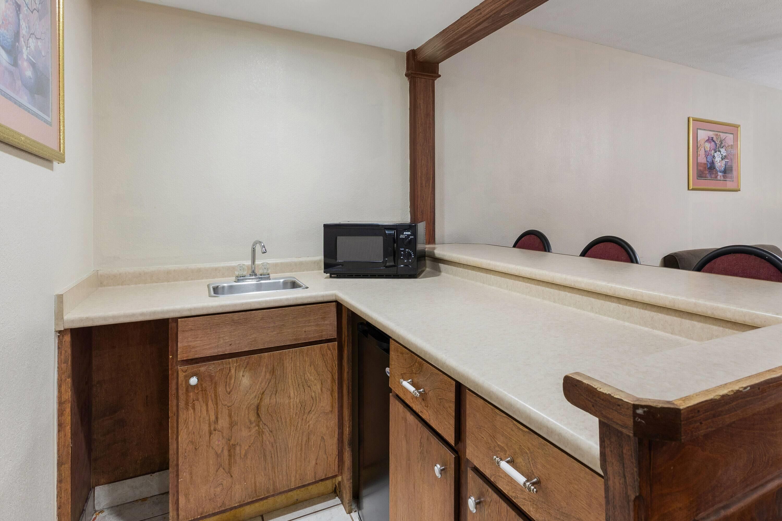 A compact kitchen with a microwave, sink, and wooden cabinets.