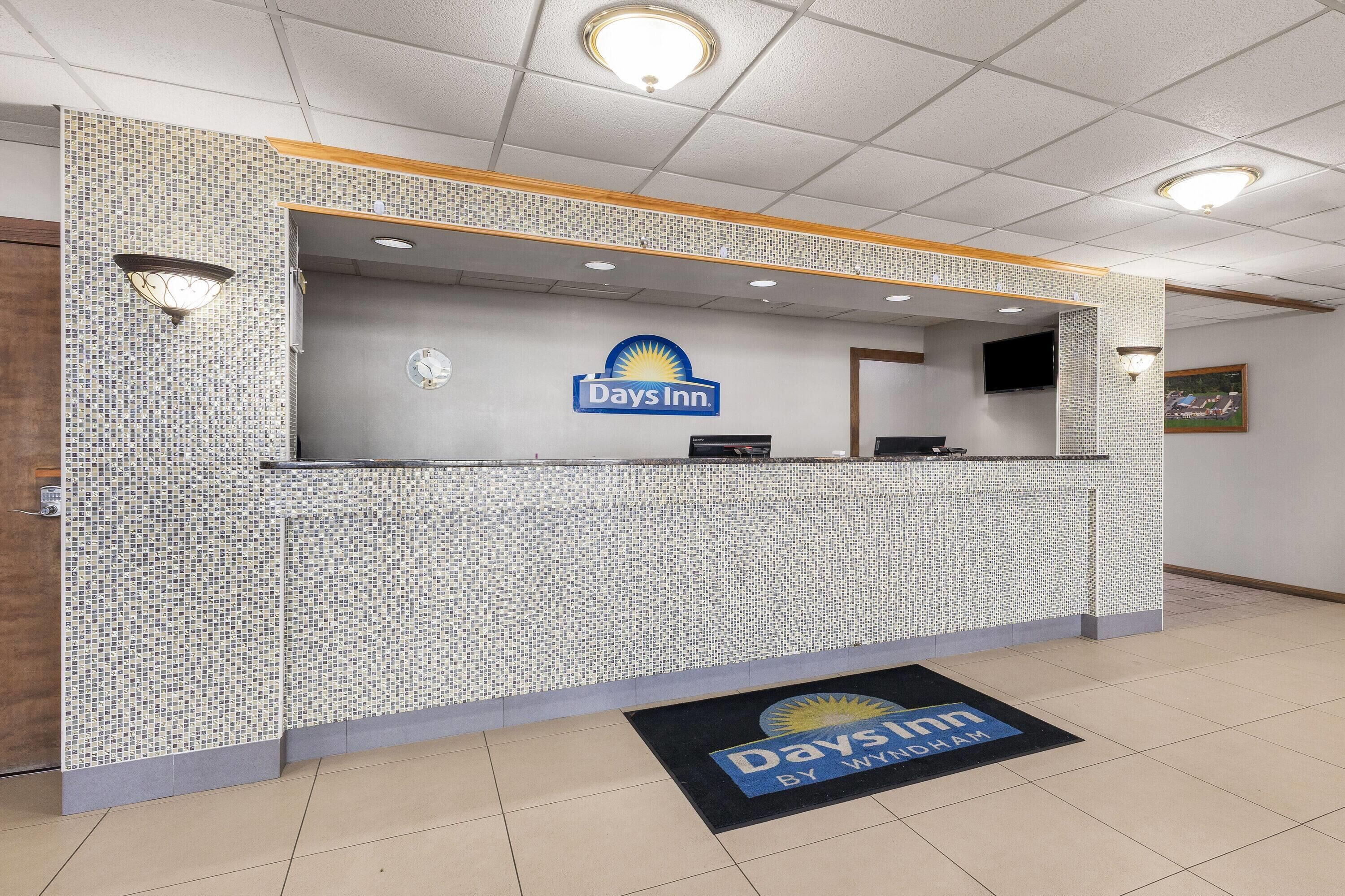 Un mostrador de recepción con diseño de mosaico, un reloj y el logotipo de Days Inn.