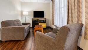 Une chambre d’hôtel équipée de deux canapés, d’une télévision, d’une petite table et d’un meuble de rangement intégré pour les appareils multimédias.