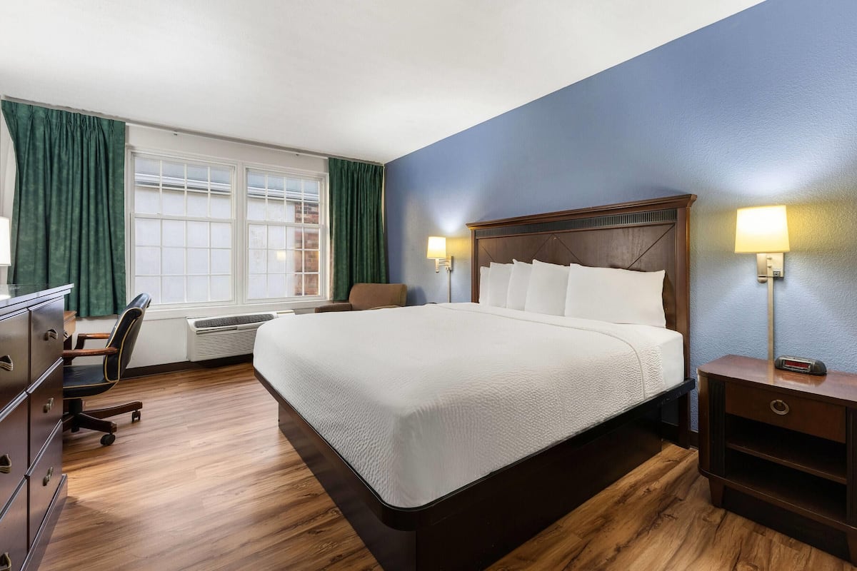 A hotel room with a large bed, a desk, and a chair.