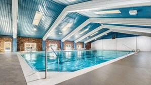 Une piscine intérieure dotée d’un plafond transparent et de murs en briques.