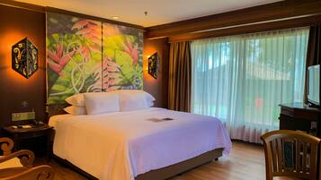 Une chambre d’hôtel avec un grand lit, un bureau, une chaise, un tableau au mur et une fenêtre avec des rideaux.