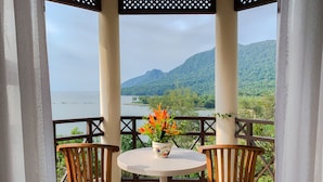 Un mirador con mesa y dos sillas, con vista a un paisaje pintoresco de un lago y montañas.