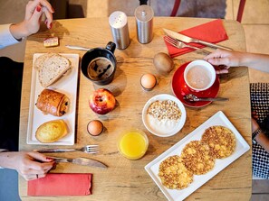 A breakfast setting with various food items and utensils on a wooden table.