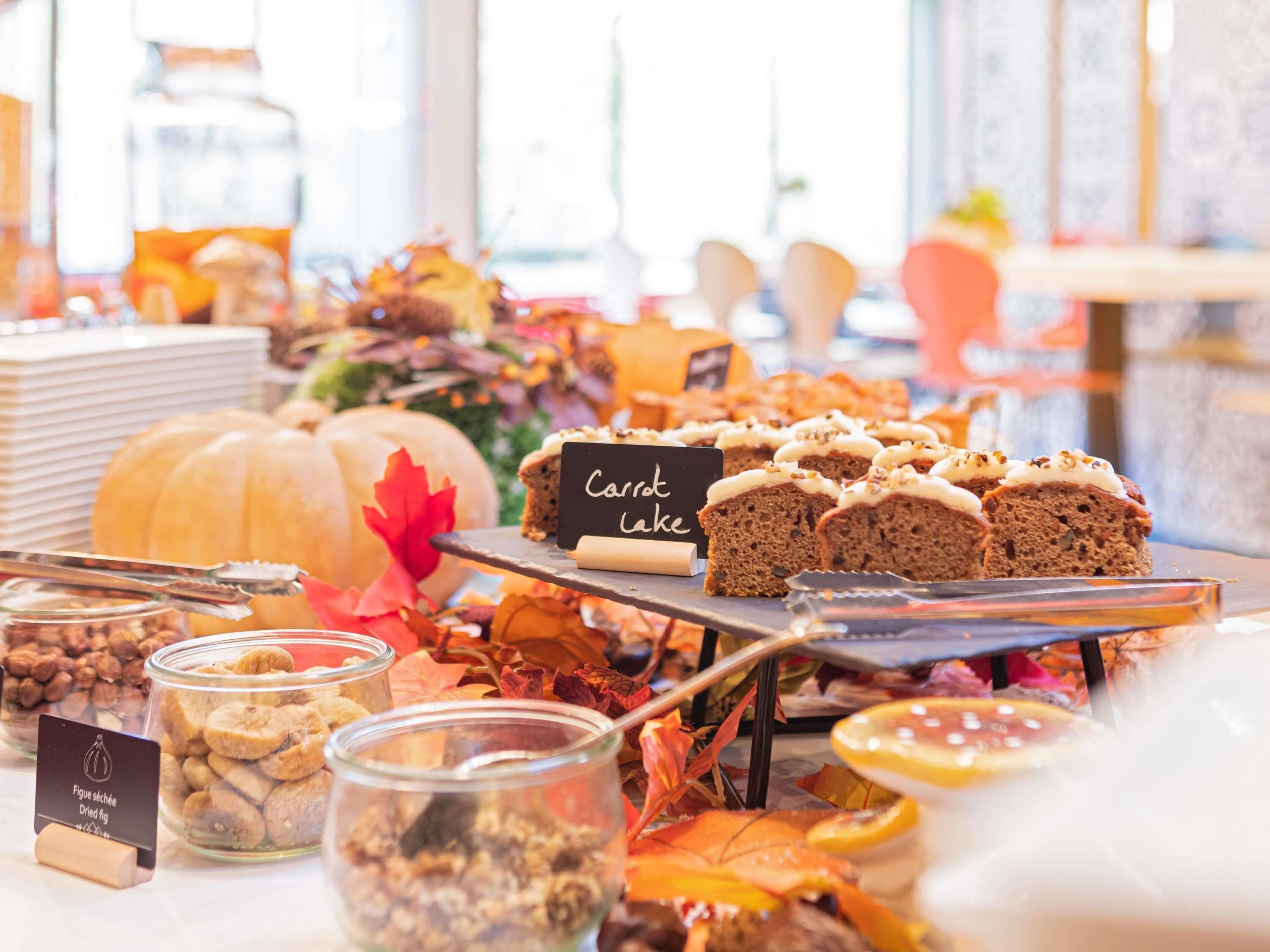Una mesa de buffet con distintos alimentos, incluyendo un cartel que indica pastel de zanahoria.