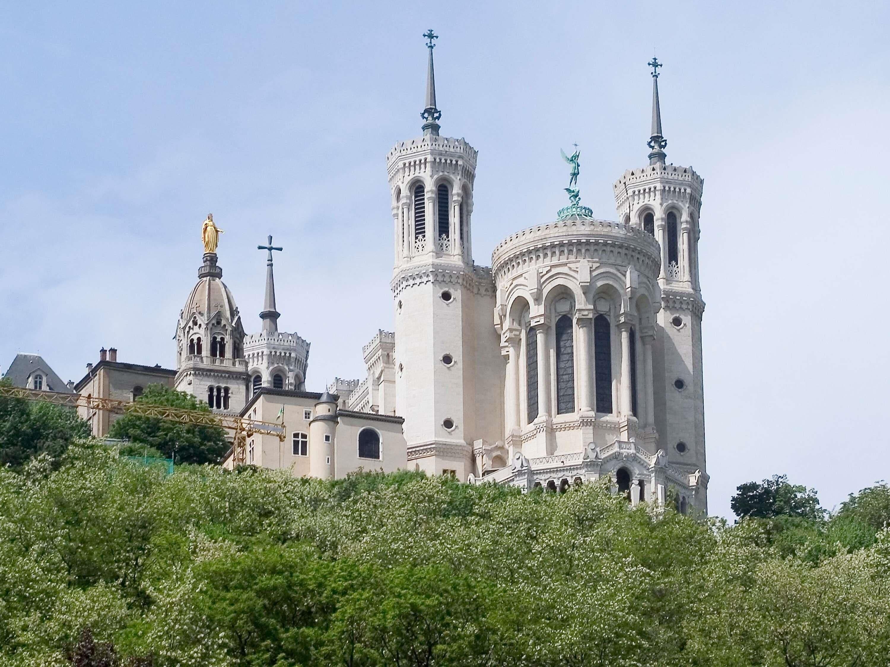 A large, ornate church with multiple spires and domes, surrounded by lush greenery.